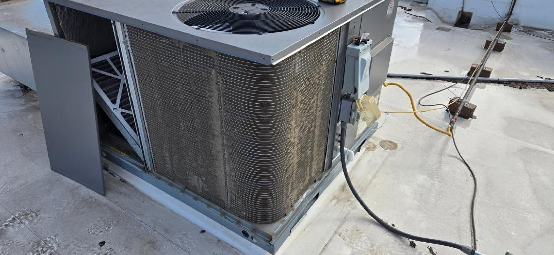 Weathered outdoor air conditioner condenser unit showing signs of age and wear on a commercial rooftop