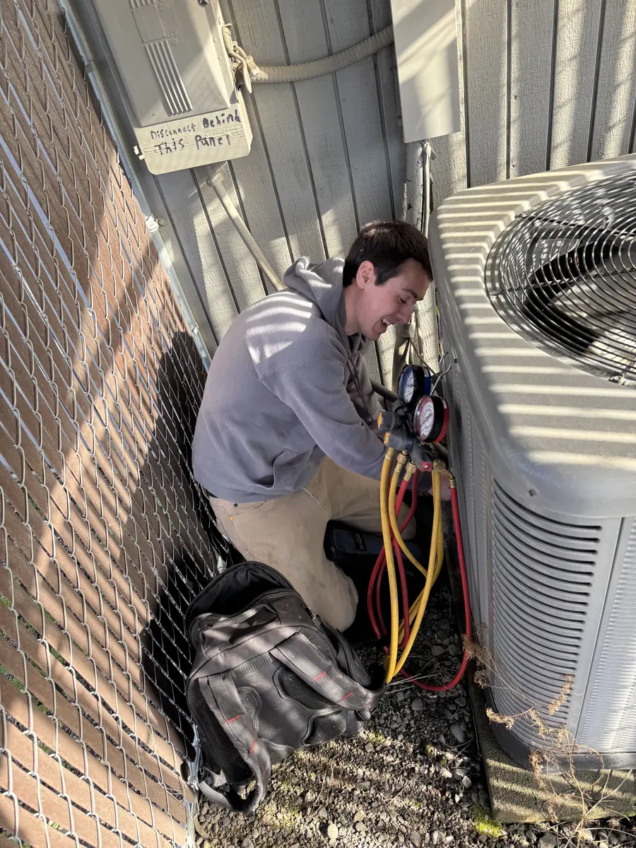 James Heating technician repairing electrical connections on an AC condenser James Heating technician repairing electrical connections on an AC condenser