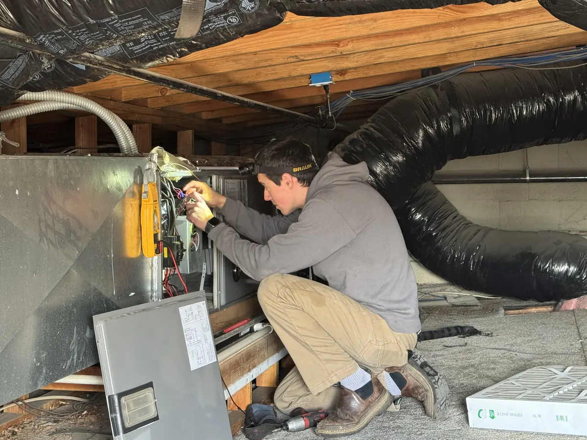 James Heating technician wiring an air handler in a crawlspace James Heating technician wiring an air handler in a crawlspace