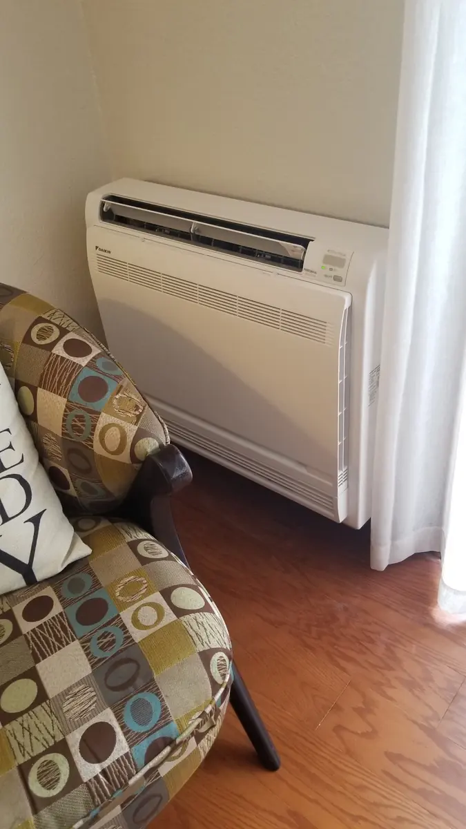 Floor-mounted ductless heat pump console in a living room Floor-mounted ductless heat pump console in a living room