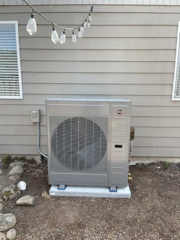 Heat pump outdoor unit on a concrete pad beside a house Heat pump outdoor unit on a concrete pad beside a house